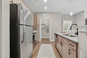 Fort Mill apartment for rent - A modern kitchen with a large refrigerator and wooden cabinets at Fox Hunt Farms apartments in Fort Mill, South Carolina.