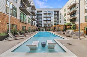 Atlanta apartment for rent - A large outdoor swimming pool surrounded by lounge chairs and buildings.