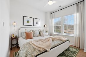 Charlotte townhouse for rent - A bedroom with a bed, two lamps, a window, and pictures on the wall.