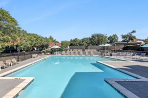 Nashville apartment for rent - A large outdoor swimming pool surrounded by lounge chairs and trees.