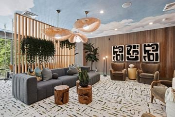 Decatur apartment for rent - A modern living room with a grey sofa, wooden chairs, and a large hanging light fixture.