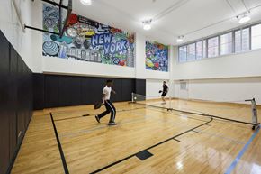 New York apartment for rent - Two people playing badminton in a gym with a mural on the wall.