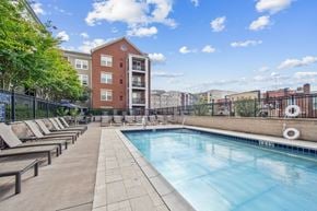 Patchogue apartment for rent - A swimming pool surrounded by lounge chairs and trees.
