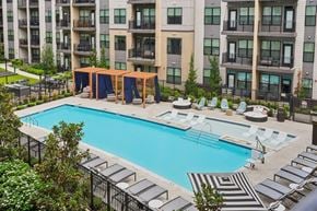 Herndon apartment for rent - A large swimming pool surrounded by lounge chairs and umbrellas.