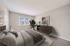 Aurora apartment for rent - A bedroom with a large bed and a nightstand with a lamp.