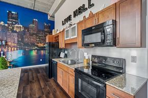 Pittsburgh apartment for rent - A kitchen with wooden cabinets and a cityscape mural on the wall.