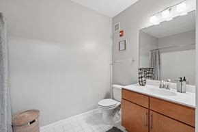 Washington apartment for rent - A bathroom with a toilet, sink, and mirror.