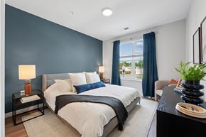 Falls Church townhouse for rent - A bedroom with a large bed and a window with blue curtains.