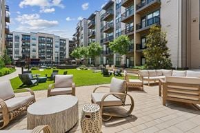 Herndon apartment for rent - A patio with chairs and tables is surrounded by apartment buildings.