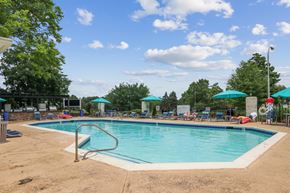 Louisville apartment for rent - A large outdoor swimming pool surrounded by trees and umbrellas.