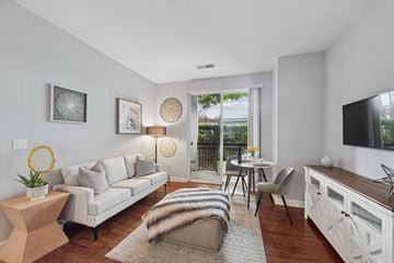 Patchogue apartment for rent - A living room with a white couch, a wooden coffee table, and a television on the wall.