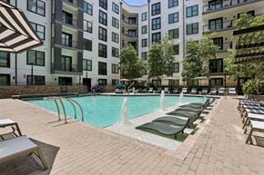 Decatur apartment for rent - A pool with a waterfall and lounge chairs in front of a building.