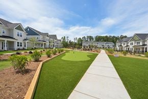 Charlotte townhouse for rent - A long concrete walkway leads through a grassy area in front of apartment buildings.