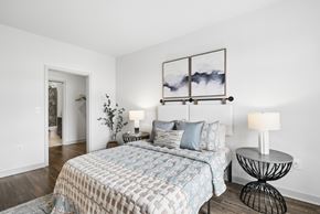 Rockville apartment for rent - A bedroom with a bed, a side table with a lamp, and a picture frame on the wall.
