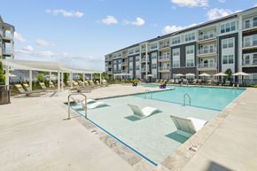 Williamsburg apartment for rent - A large swimming pool with lounge chairs and umbrellas in front of apartment buildings.
