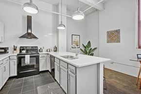 Pittsburgh apartment for rent - A modern kitchen with a black stove top oven and white cabinets.