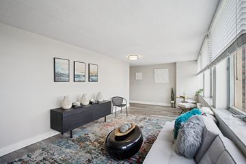 Cleveland apartment for rent - A living room with a grey couch, a black table, and a painting on the wall.