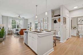 Matthews apartment for rent - A kitchen with a white island and a dining area with a table and chairs.