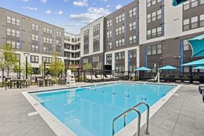 Hyattsville apartment for rent - A swimming pool in front of a building with a blue umbrella.