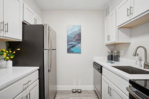 Cleveland apartment for rent - A kitchen with white cabinets and a black fridge.