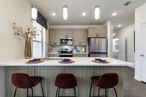 Pflugerville apartment for rent - A modern kitchen with a bar area and red chairs.