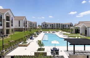 Pflugerville apartment for rent - A pool surrounded by a black fence and a building in the background.
