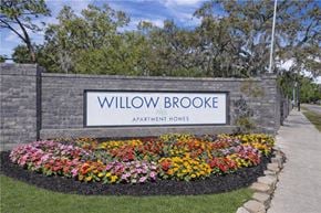 Tampa apartment for rent - A sign for Willowbrooke Apartment Homes is framed by a flower bed. at Willow Brooke Apartments, Tampa, 33613