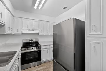 Tampa apartment for rent - A black refrigerator stands in a kitchen with white cabinets.