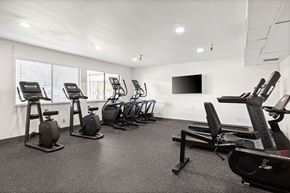 Mountain View apartment for rent - A gym with a row of exercise bikes and a television mounted on the wall.