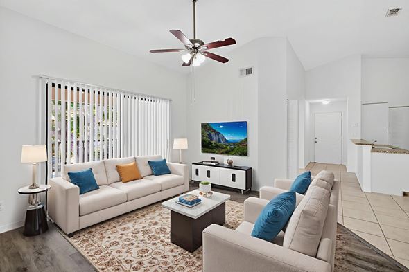 Naples condo for rent - A living room with a white couch and a ceiling fan.