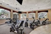 Las Vegas apartment for rent - A gym with a row of exercise bikes and a television mounted on the wall.