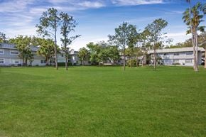 Tampa apartment for rent - A grassy field with trees and buildings in the background. at Willow Brooke Apartments, Apartments, Tampa, FL