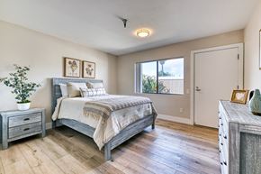 Vista apartment for rent - A bedroom with a bed, nightstand, and a plant.