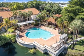 Naples condo for rent - A large swimming pool surrounded by a deck and a covered patio area.