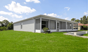 Lehigh Acres triplex for rent - A modern house with a grey exterior and a green lawn in front.