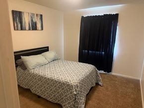 Huron apartment for rent - A bedroom with a patterned bedspread and a black headboard.