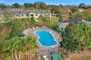 Pace apartment for rent - A pool surrounded by a fence and trees.
