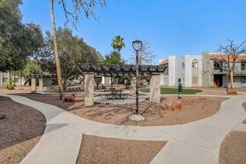 Las Vegas apartment for rent - A park area with a bench and a tree in front of a building.