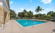 Naples apartment for rent - A large outdoor swimming pool surrounded by a concrete patio and palm trees.