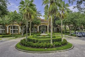 Sanford apartment for rent - A building with a landscaped front yard and palm trees.