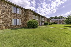 Pensacola condo for rent - A grassy area in front of a brick building with a cloudy sky above.