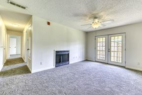 Pensacola condo for rent - A living room with a fireplace and a ceiling fan.