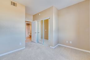 Las Vegas condo for rent - an empty bedroom with mirrored closet doors and carpeting