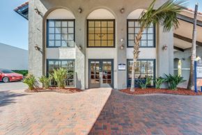 San Diego apartment for rent - the front entrance of a building with a brick sidewalk and palm trees