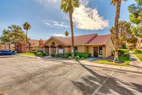 Las Vegas apartment for rent - a building with a parking lot and palm trees