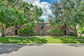 Tampa apartment for rent - A house with a driveway and trees in front at Green Oaks Apartments, Apartments, Tampa, FL