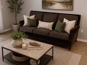 Dallas apartment for rent - A living room with a brown couch, a coffee table, and a plant.