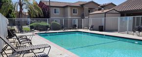 Corcoran apartment for rent - A pool surrounded by a fence with chairs around it.