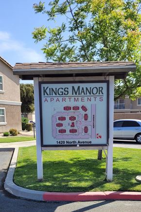 Corcoran apartment for rent - A Kings Manor Apartments sign is in front of a tree and a building.