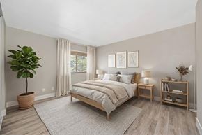 Fair Oaks apartment for rent - A bedroom with a large bed, a potted plant, and a nightstand with a lamp.